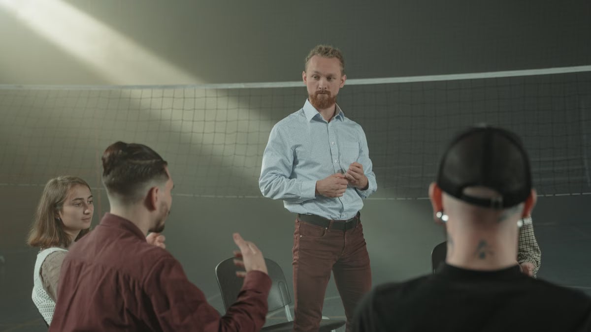 Four people engaged in a group discussion inside a room with a net background.